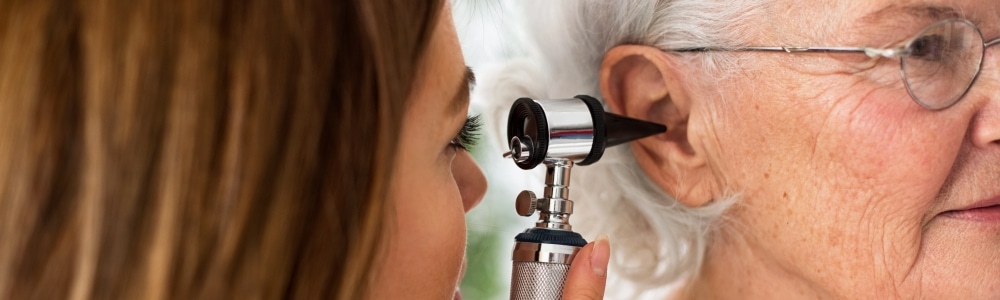 Doctor using an otoscope to look into elderly woman's ear